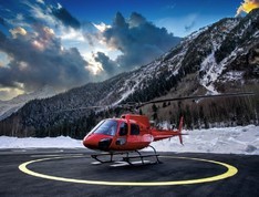 Private helicopter on a helipad next to mountains