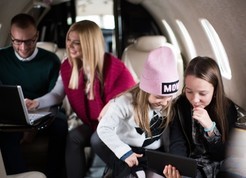 Young family using laptops and iPads in private jet cabin