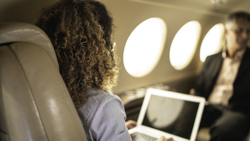 Businesswoman looks at laptop in Beechcraft King Air cabin